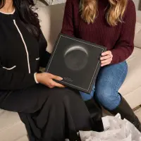 Two friends on a sofa holding a square moon phase canvas
